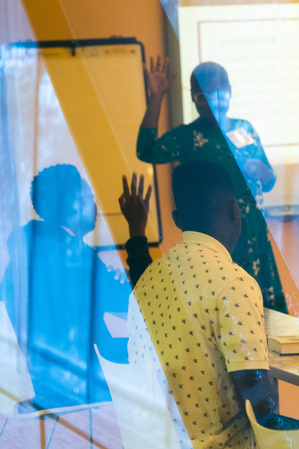 Students raising their hands through colorful reflective glass