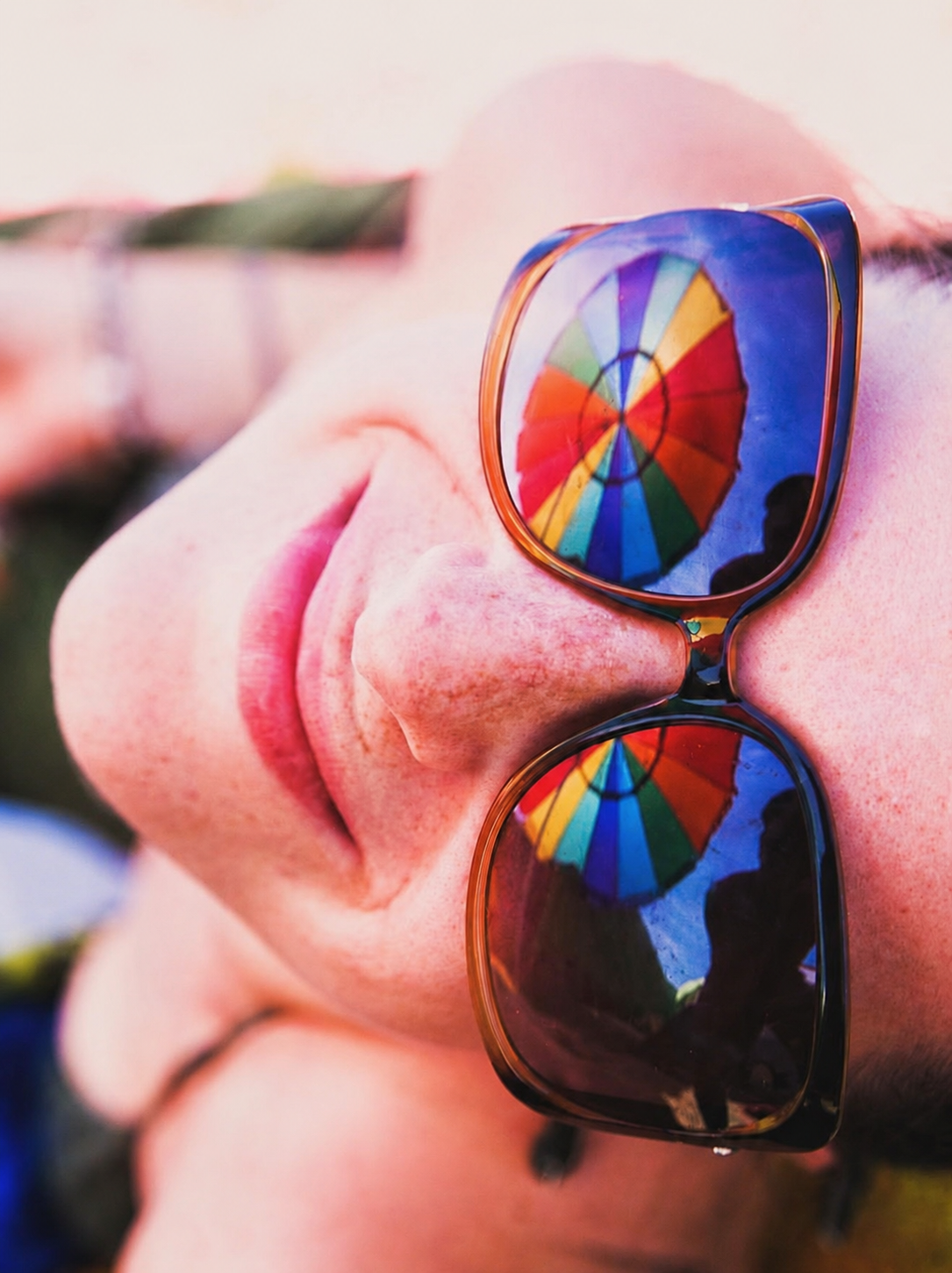 Close portrait reflected in vivid rainbow sunglasses